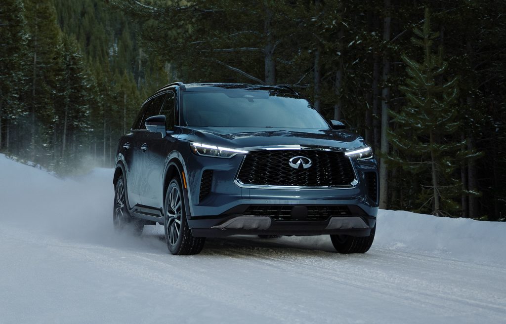 Picture of an INFINITI QX60 driving down a snowy backroad in the forest.